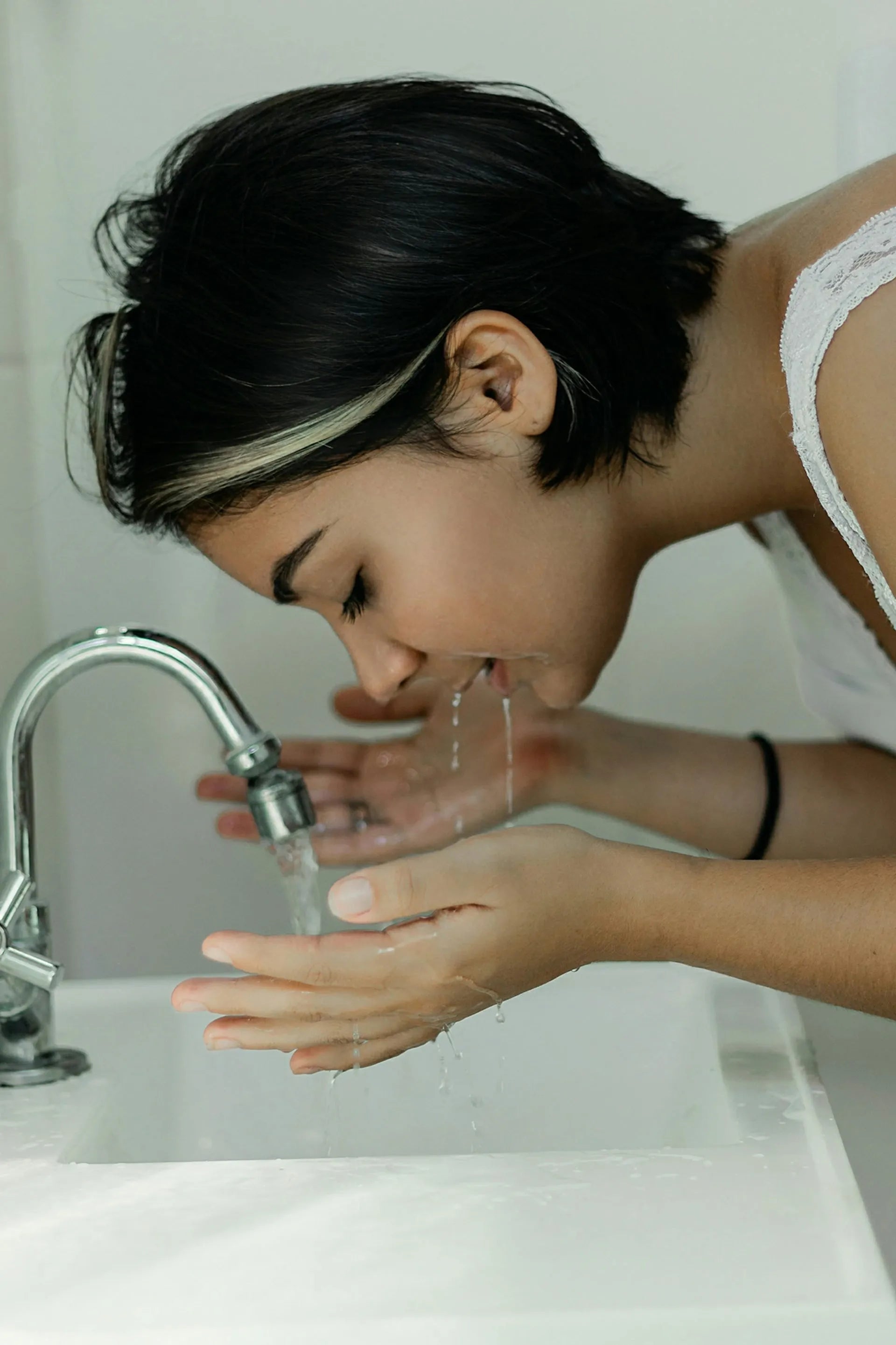 Woman rinsing her face at a sink