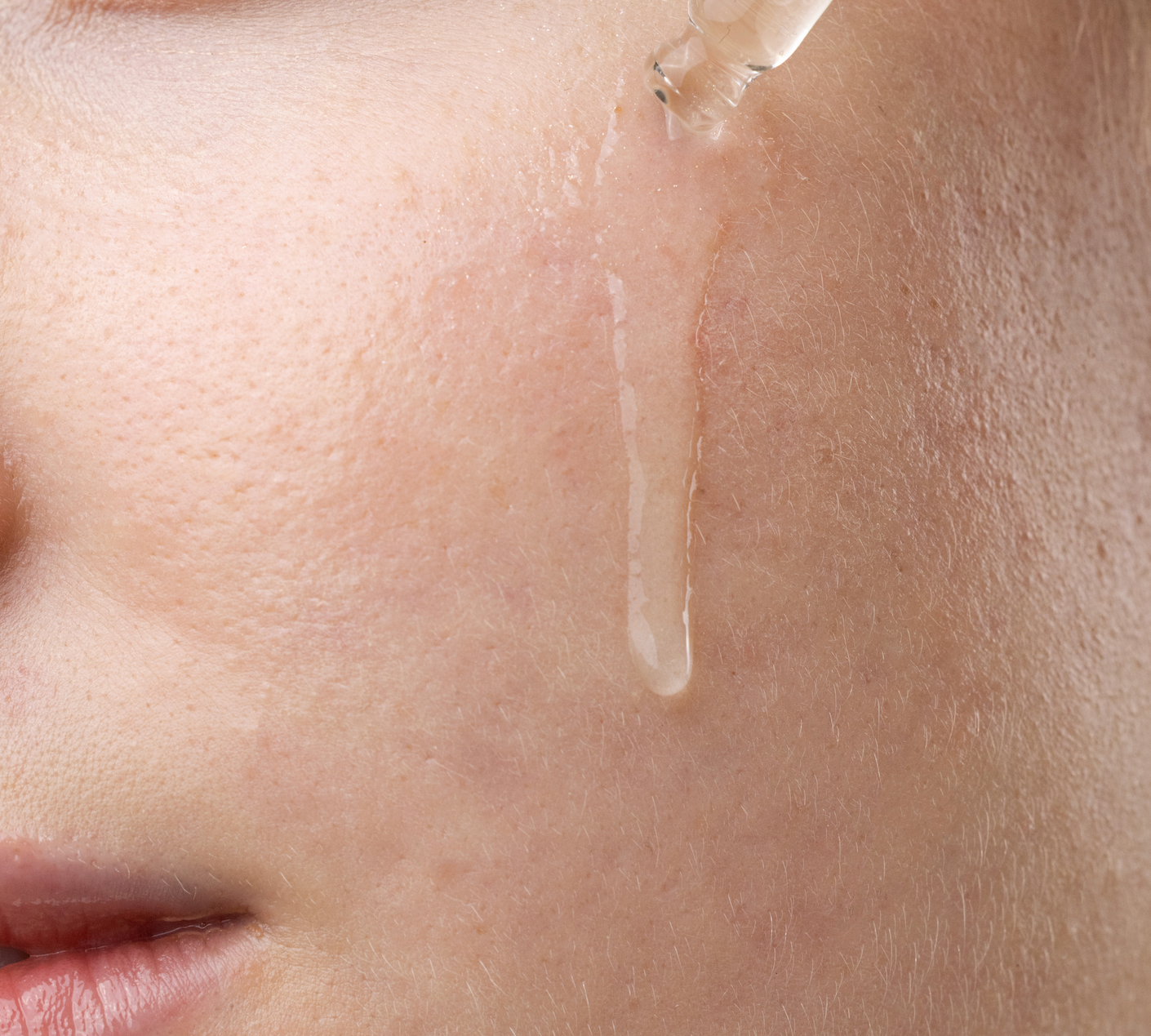 Serum dropper releasing a drop onto a cheek