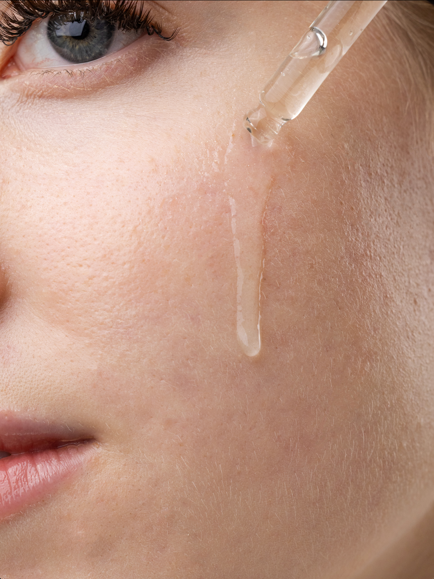 Serum dropper releasing a drop onto a cheek