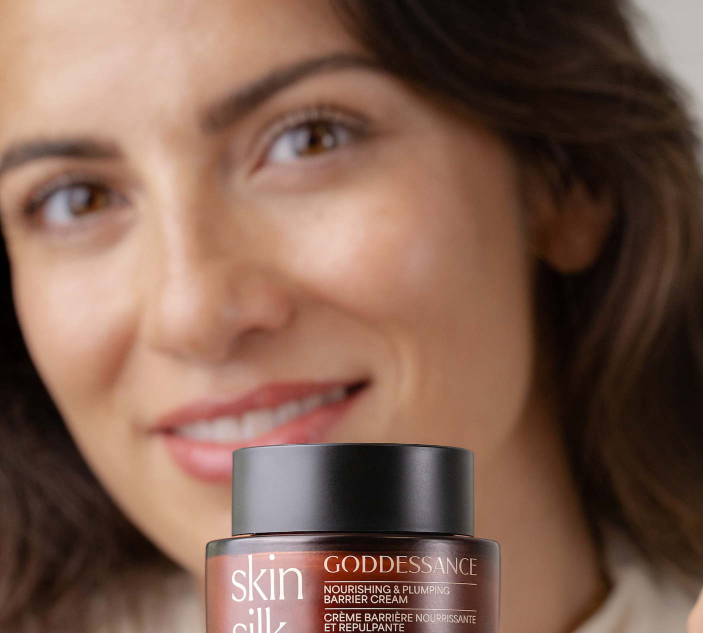 Smiling woman holding a Skin Silk barrier cream jar